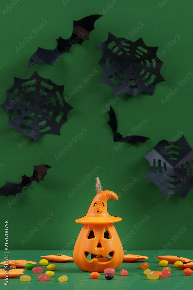 Obraz premium Halloween celebration concept with jack-o'-lantern bucket candy and paper bats on green background