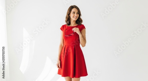 Young woman in red dress holding glasses and smiling