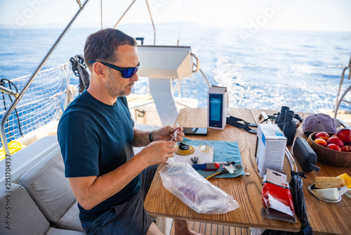 Quadro su tela Man repairing yacht equipment with hand tools during a sailing trip on the Adriatic Sea