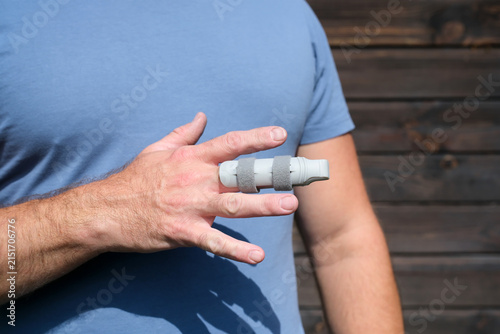 Canvas Print Man in workwear holding injured finger with splint, workplace accident and occup