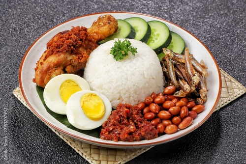 nasi lemak served on a plate with fragrant coconut rice, spicy sambal, fried anchovies, roasted peanuts, boiled egg, and fresh cucumber slices. Favorit Malaysian Food