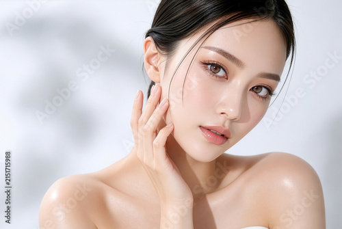 艶のある黒髪の若い女性が頬に手を添える透明感のある美肌とナチュラルメイクの美容ポートレー
