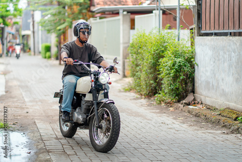 Helmeted Indonesian Man Riding Motorcycle on Residential Street