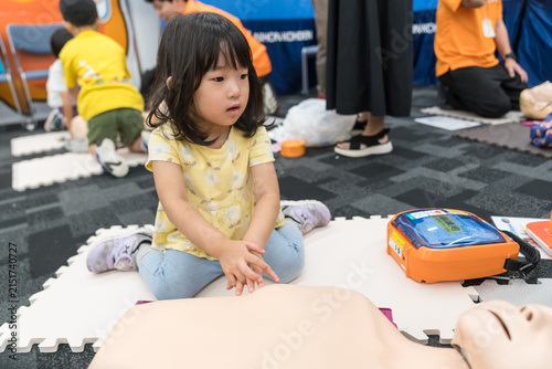 救急救命体験イベントでAEDに触れる日本人の女の子の幼児