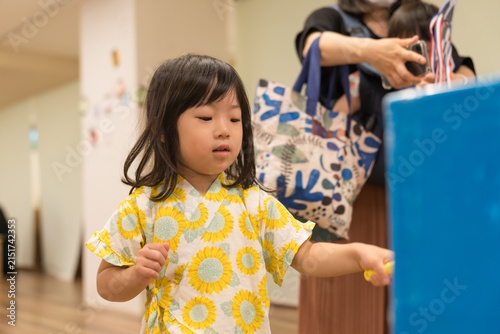 ひまわり柄の甚平を着ておもちゃのハンマーでゲームをする日本人の女の子の幼児