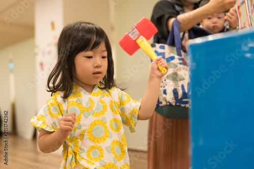 ひまわり柄の甚平を着ておもちゃのハンマーでゲームをする日本人の女の子の幼児