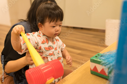 スイカ柄の甚平を着たおもちゃのハンマーで遊ぶ日本人の男の赤ちゃん
