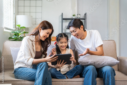 Asian family smiling together watching digital tablet