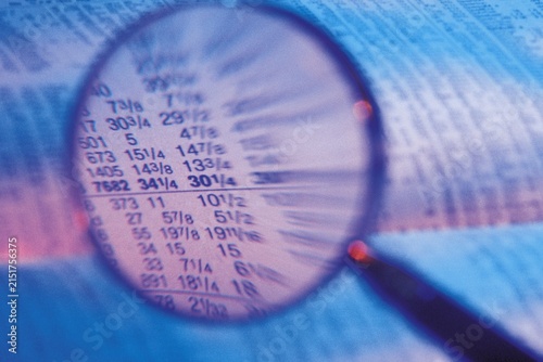 Konstfotografi Magnifying glass focused on tabular financial market price data with magnifying
