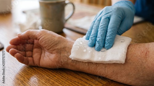 Caregiver placing a clean compress on elderly wrist for wound care at home