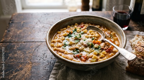 Pasta e Fagioli: Close-up of a rustic bowl of short pasta and bean soup, a classic, thick 'comfort food' with a spoon resting in it.
