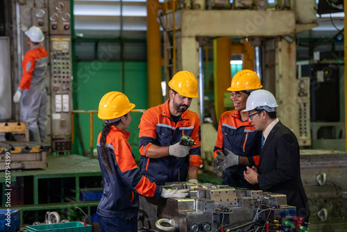 Factory engineer team safety helmet, industrial worker group inspecting metal mold machinery on manufacturing floor