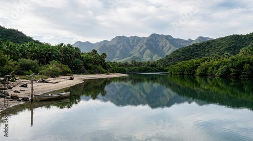 Serene coastal lagoon reflecting lush green mountains and tropical foliage under an overcast sky, with a small boat near the sandy shore
