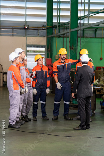 Engineer factory worker helmet safety team industry uniform manager group meeting on production floor with machinery