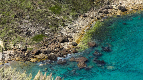 Принти на полотні Clear turquoise shallows meeting a boulder strewn shoreline below green chaparra