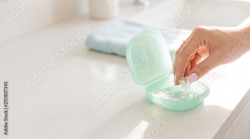 Hand Reaching for Mouthguard in Mint Green Case on Counter