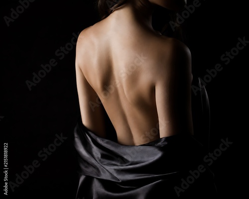 Quadro su tela Woman's bare back with smooth skin in dramatic studio lighting with silk fabric