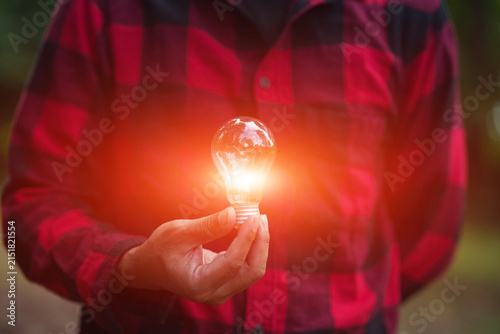 Man in Plaid Shirt Holding Glowing Light Bulb for Energy and Innovation Concept