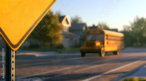 School zone warning sign with a yellow school bus arriving on a sunny suburban street, representing the start of the back to school season, student commute, and the start of a new academic year