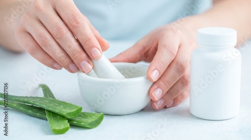 Hands Crushing Aloe Vera Leaves in a Ceramic Mortar and Pestle for Natural Herbal Medicine and Skincare Preparation