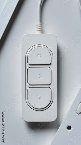 White remote control with three buttons on a gray surface.