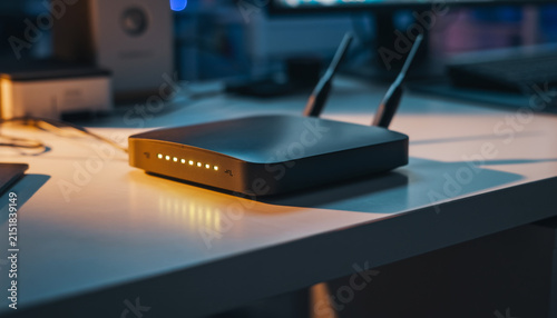 Wireless router with illuminated indicator lights on a desk.