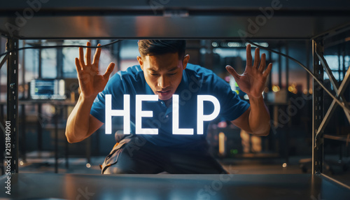 Young man looking distressed behind a glass window with the word HELP.