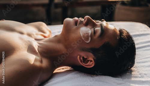 Young man lying on bed with eye patches resting peacefully.