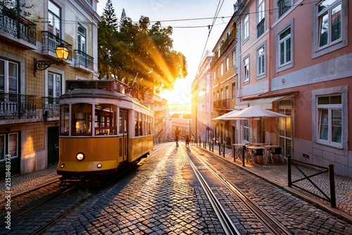 Lisbon street at sunset with historic yellow tram ascending cobbled hill, warm light reflecting on traditional buildings