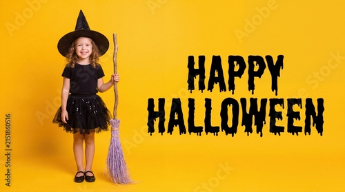 Little girl in witch costume holding a broomstick for Halloween
