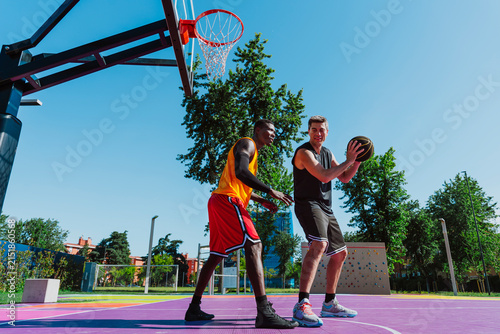 A man defends his opponent during an outdoor basketball game
