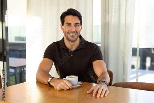 A handsome man drinks coffee at a cafe table
