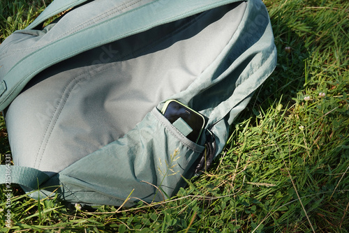 smartphone tucked away in green backpack pocket resting in nature as digital detox concept