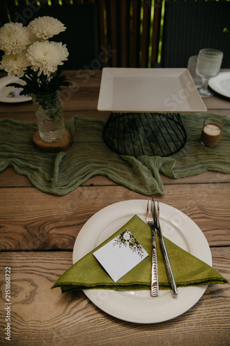 Banquet table in a restaurant for a wedding or anniversary celebration with served dishes, flowers, a triangular napkin, ladles and spoons