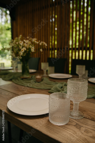 Banquet table in a restaurant for a wedding or anniversary celebration with served dishes, flowers in vases, napkins, ladles, spoons