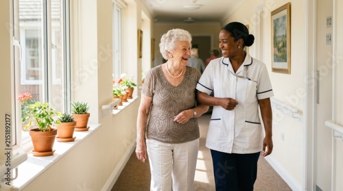 Happy senior woman walking with a caring young nurse in a bright assisted living facility hallway, showing supportive geriatric care and professional medical assistance for elderly residents in