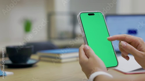 Close-up Of Smartphone With Green Mock-up Screen In Women's Hands On Desktop Background. Woman Using Mobile Phone, Browsing Internet, Social Networks, Financial Reports