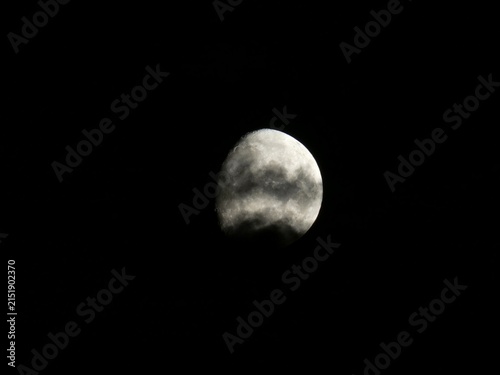 Cuadro en lienzo Waxing gibbous moon partially covered by dark cloud stripes in night sky