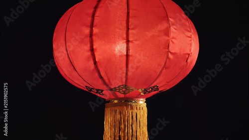 Red paper lantern with gold tassel against a dark background