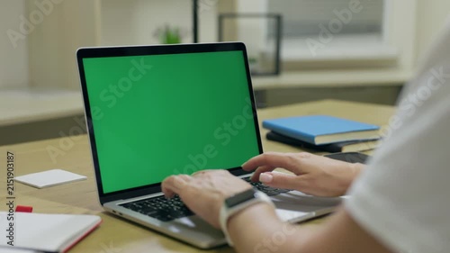 Woman Typing On Laptop Computer with Green Screen Chroma Key At Home Office Space. Female Freelancer Browsing Green Laptop Screen Using Keyboard and Touchpad