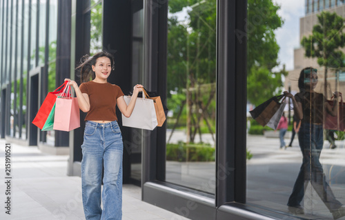 Bild auf Leinwand Smiling asian woman walking and holding shopping bags, Fashion shopping, retail