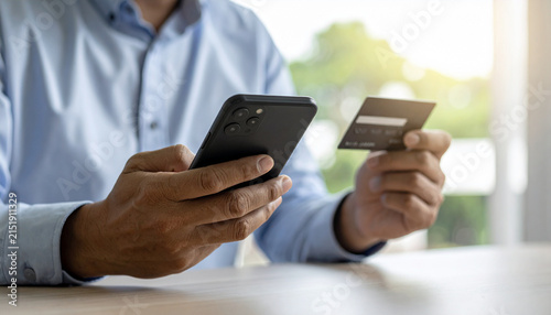 Close-up of hands using a smartphone for online banking with a credit card in the other hand
