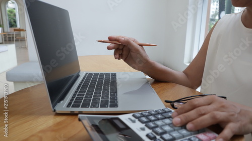 Professional business and financial planning concept featuring an entrepreneur working with a laptop, calculator, smartphone, and digital tablet at a wooden desk