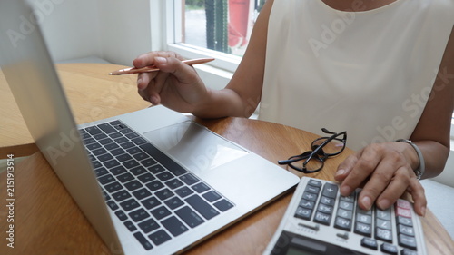Professional business and financial planning concept featuring an entrepreneur working with a laptop, calculator, smartphone, and digital tablet at a wooden desk