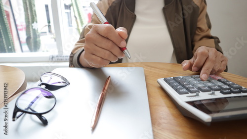 Professional business and financial planning concept featuring an entrepreneur working with a laptop, calculator, smartphone, and digital tablet at a wooden desk