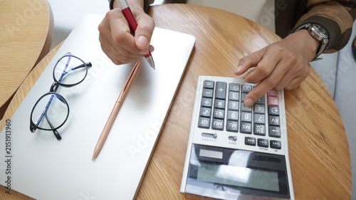 Professional business and financial planning concept featuring an entrepreneur working with a laptop, calculator, smartphone, and digital tablet at a wooden desk