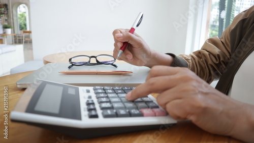Professional business and financial planning concept featuring an entrepreneur working with a laptop, calculator, smartphone, and digital tablet at a wooden desk