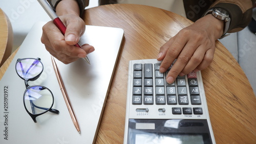 Professional business and financial planning concept featuring an entrepreneur working with a laptop, calculator, smartphone, and digital tablet at a wooden desk