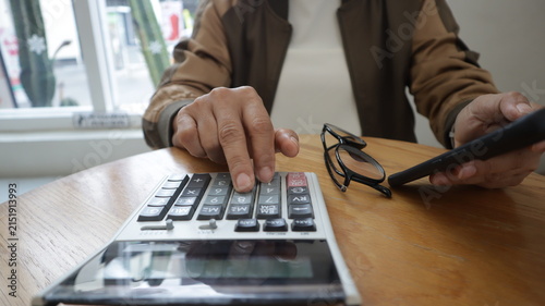 Professional business and financial planning concept featuring an entrepreneur working with a laptop, calculator, smartphone, and digital tablet at a wooden desk