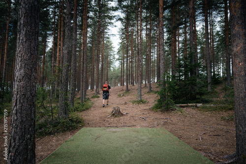 disc golf player walking in the woods